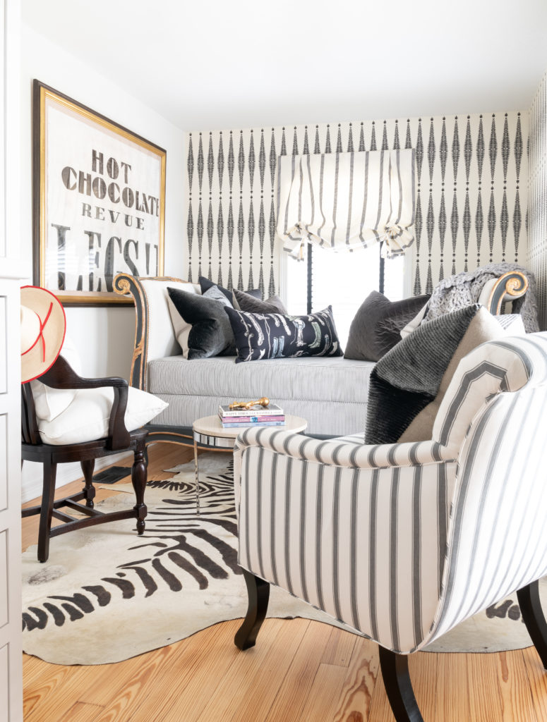 The upstairs dressing area evokes the feeling of a small European hotel, with ticking and striped fabrics, Schumacher wallpaper, and printed zebra rug. Lumbar pillow made from a vintage silk Hermès scarf from Tribute Goods. Artwork by Houston talent Tierney Malone. (Photo Jack Thompson.)