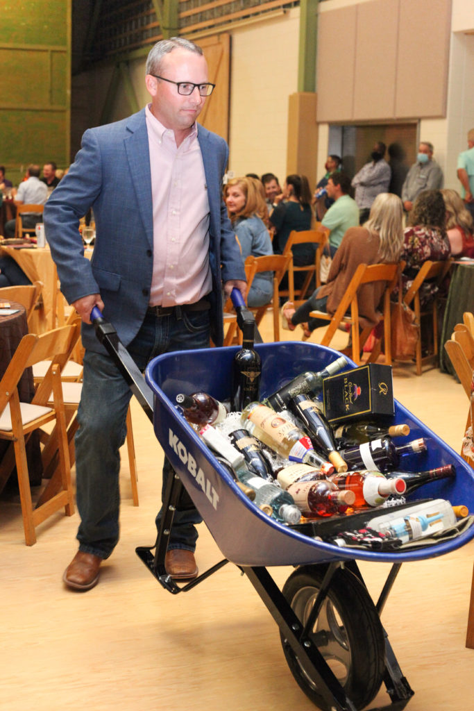 Kyle Marten tempts the auction crowd with his wheelbarrow o' booze.